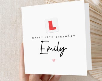 May include: White card with a red "L" symbol, the text "Happy 17th Birthday Emily" and a pink heart.