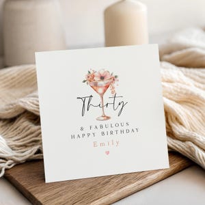 May include: A square birthday card with a cocktail illustration. The card features the word "Thirty" in elegant script, along with "& Fabulous Happy Birthday Emily" and a small heart. The cocktail glass is adorned with flowers.