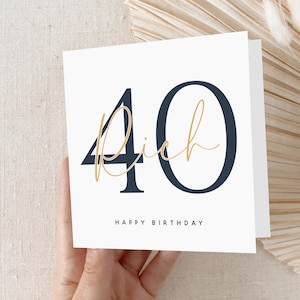 May include: A white card with a navy blue and gold design. The number 40 is written in large navy blue font with the word "rich" written in gold cursive script. The text "Happy Birthday" is written in black below the number.
