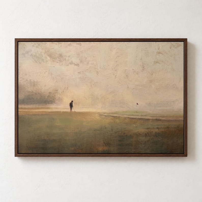 Puede incluir: Un cuadro de paisaje enmarcado que muestra una figura solitaria en un campo de golf en un entorno brumoso de tonos beige y verdes. La obra representa a un golfista sosteniendo un palo cerca de una bandera, con pinceladas visibles y texturizadas.
