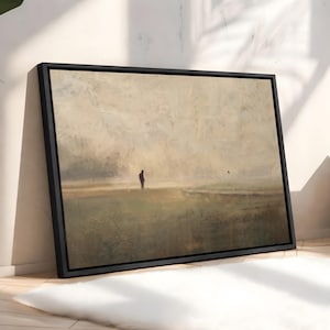 Puede incluir: Un cuadro de paisaje enmarcado en negro que muestra una figura solitaria de pie en un campo vasto y brumoso con tonos beige, marrones y verdes apagados. La obra representa una amplia extensi&oacute;n abierta con una atm&oacute;sfera neblinosa.