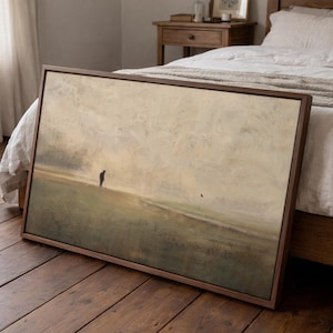 Puede incluir: Una pieza de arte mural rectangular enmarcada que presenta una pintura de paisaje con una paleta de colores apagados en beige, bronceado y verde oliva. La obra muestra un campo vasto y brumoso bajo un cielo nublado con una figura solitaria.
