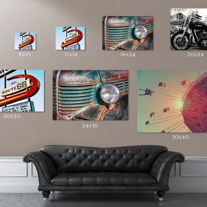 K&ouml;nnte beinhalten: Eine Collage aus sechs Vintage-inspirierten Fotografien mit einem rostigen LKW, einem Motorrad, einem Neon-Schild f&uuml;r ein Motel an der Route 66 und einem Riesenrad. Die Fotos sind an einer Wand &uuml;ber einem schwarzen Ledersofa angebracht.