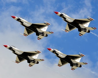 Peut inclure: Quatre avions de chasse blancs, rouges et bleus volent en formation contre un ciel bleu avec des nuages blancs. Les avions sont peints avec un motif d'aigle noir.