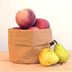 Peut inclure: Un sac en papier brun rempli de pêches mûres et deux poires vertes sur une surface en bois.