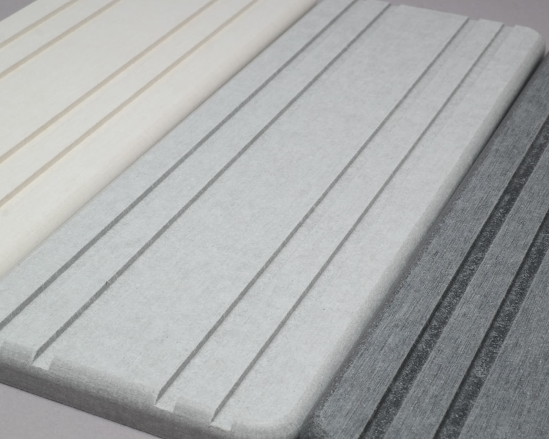 May include: Close-up of three rectangular, textured, light-colored surfaces with parallel grooves. The surfaces are in shades of white, gray, and dark gray. The grooves run diagonally across the surfaces, creating a textured pattern.