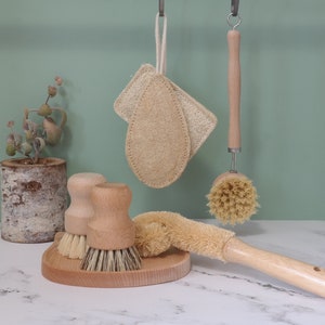 Peut inclure: Un ensemble de quatre outils de nettoyage naturels, comprenant deux éponges en loofah, une brosse en bois avec des poils naturels et une brosse en bois avec un manche en loofah.