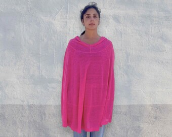 Könnte beinhalten: Ein leuchtend neonpinker Poncho mit einem weiten, abgerundeten Ausschnitt und einer lockeren, fließenden Silhouette. Das Kleidungsstück hat eine leichte, halbtransparente Strickstruktur, die über Schultern und Rumpf fällt und gerade endet.