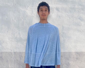 Könnte beinhalten: Ein hellblauer, locker sitzender, halbtransparenter Poncho mit rundem Halsausschnitt und sichtbaren horizontalen Nahtdetails im Brust- und Mittelbereich, kombiniert mit einer dunkelblauen Jeans.