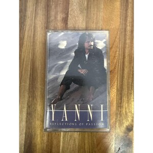 Op de afbeelding: Een vintage cassettebandje met de artiest Yanni. De hoes toont Yanni in een zwart pak, zittend op een rotsachtige ondergrond. Op de band staat "Yanni Reflections of Passion" in witte tekst op een donkerblauwe achtergrond.