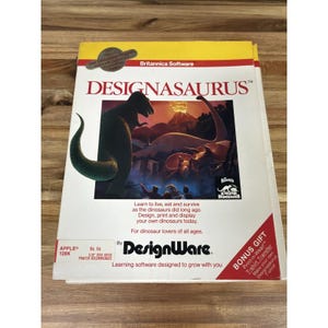 May include: A vintage "Designasaurus" software box with a dinosaur illustration. The box features the "Britannica Software" logo and text promoting the software's educational and creative aspects. Includes a bonus gift of a t-shirt transfer.