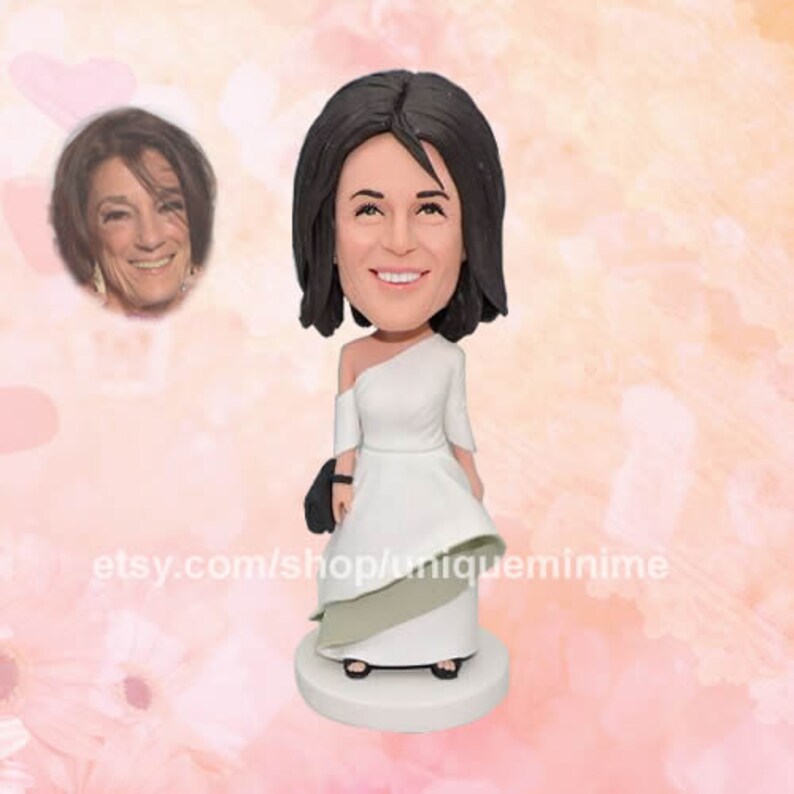 May include: A custom-made figurine of a person wearing a white dress with a green and white layered skirt. The figurine has a realistic face and brown hair.