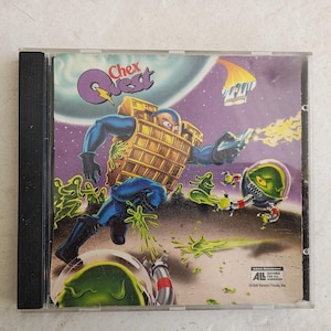 May include: A Chex Quest PC game CD case. The cover art features a cartoon character in a yellow and blue suit, shooting at green alien-like creatures. The background is a purple space scene with the game's logo.