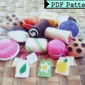 May include: A collection of felt food items, including a donut, a roll, a cookie, a macaron, and a cupcake. The items are arranged on a woven surface with a tag that says "PDF Pattern".