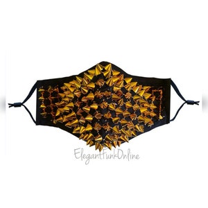 May include: Black face mask embellished with gold-colored cone studs. The mask has adjustable black ear loops and features the text "ElegantFunkOnline" in a script font.