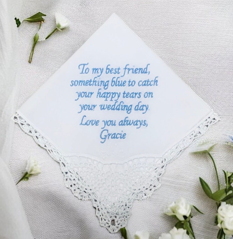 Our customizable white Something New,  Something Blue handkerchief on a white background with white flowers scattered around it.