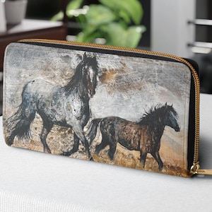 May include: A black zippered wallet with a colorful abstract design featuring two horses running through a field. The horses are painted in shades of gray, brown, and black.