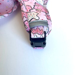 May include: Pink dog collar with a cookie pattern and a black plastic buckle.