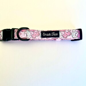 May include: A pink and white dog collar with a black buckle and a white label that says "Smash Face".