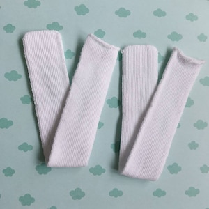 May include: Two white ribbed fabric strips, possibly for sewing or crafting projects.