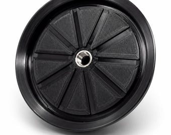 May include: A black, circular object with a central metal component. The object has a textured, geometric pattern radiating from the center. The outer rim is smooth and rounded.