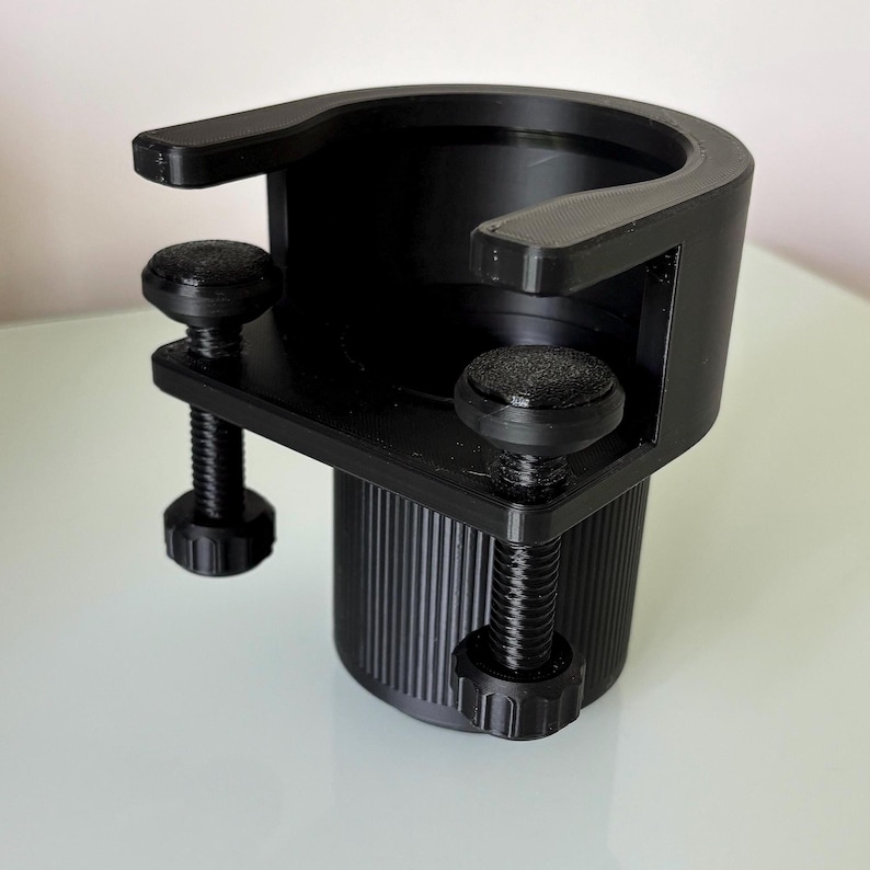May include: Black plastic cup holder with two adjustable clamps. The holder has a threaded design and can be attached to a variety of surfaces.