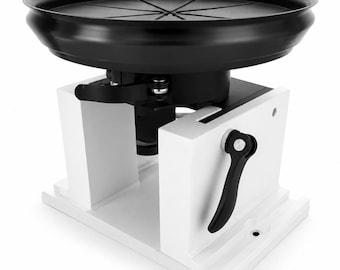May include: A white and black machine with a circular black top. The machine has a white base with a black handle on the side. The top has a ridged design. The machine is designed for a specific purpose.