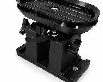 May include: A black camera tripod head with an oval top and adjustable levers. The top has a ridged surface with a central screw mount. The base is rectangular with a series of slots and holes. The tripod head is designed to support a camera.