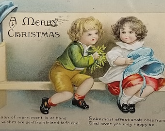 Christmas Postcard Children on Bench Boy Offering Mistletoe Artist Ellen Clapsaddle IAP Publishing