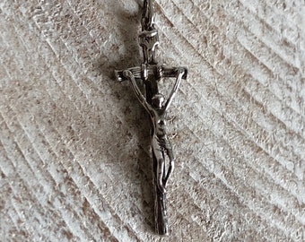 Puede incluir: Pendiente de cruz de plata con una figura detallada de Jesucristo en la cruz.