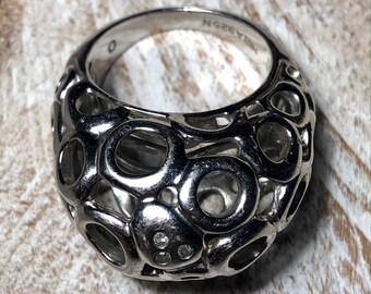May include: A silver ring with a unique design featuring a cage-like structure with small round openings. The ring has a row of small clear stones set in the center.