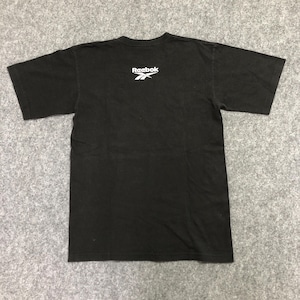 Puede incluir: Camiseta negra con el logo blanco de Reebok en la parte superior de la espalda. La camiseta tiene mangas cortas y cuello redondo. La tela parece ser de algod&oacute;n o una mezcla de algod&oacute;n.