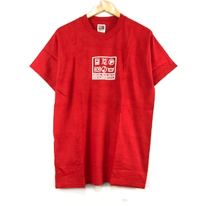 May include: Red short-sleeved t-shirt with a white care label graphic on the front. The care label graphic includes symbols for washing, drying, ironing, and bleaching. The text on the care label reads "MADE IN JAPAN, 100% COTTON, DRY CLEAN ONLY, TURN INSIDE OUT, WASH COLD, LOW TUMBLE DRY, DO NOT BLEACH, DO NOT IRON."