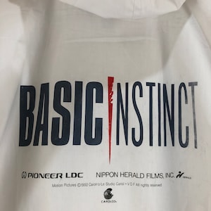 May include: White hooded jacket with the text "BASIC INSTINCT" in black letters and a red slash. The text "PIONEER LDC" and "NIPPON HERALD FILMS, INC." are printed in black below the title. The text "Motion Pictures ©1992 Carolco/Le Studio Canal + V.O.F All rights reserved." is printed in black below the company names. The text "CAROLCO." is printed in black below the copyright information.