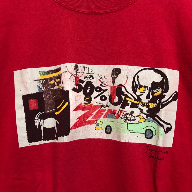 Puede incluir: Camiseta roja de cuello redondo con estampado gr&aacute;fico. El estampado presenta una calavera, figuras y texto, incluyendo "50% OFF" y "ZEN". El dise&ntilde;o es en negro, blanco, amarillo y verde. La firma del artista est&aacute; en la parte inferior.