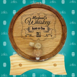 May include: A wooden barrel with a metal band and a wooden tap. The barrel is decorated with a personalised label that reads "Michael's Whiskey Aged in Oak Since 1940".