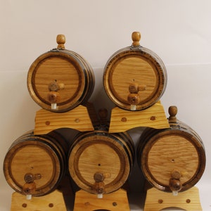 May include: Six wooden barrels with black metal bands and wooden spigots, arranged in a pyramid shape on wooden stands.