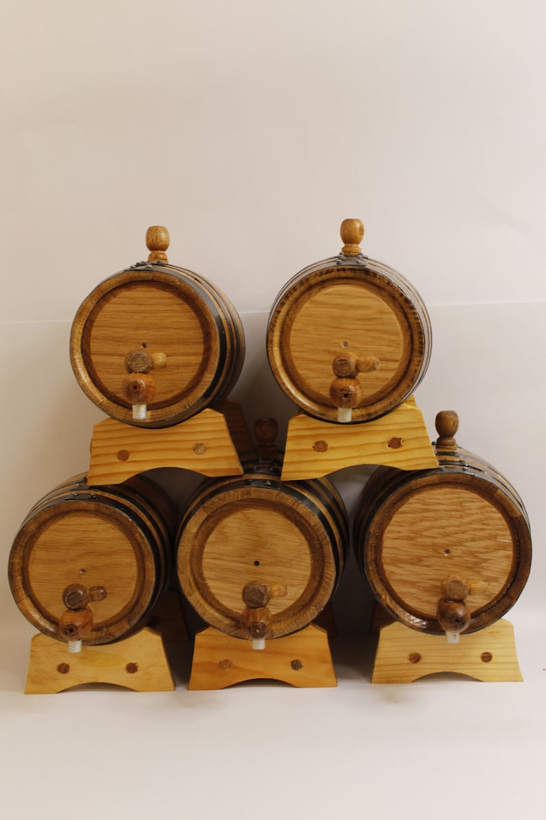 May include: Six wooden barrels with black metal bands and wooden spigots, arranged in a pyramid shape on wooden stands.