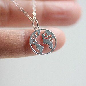 May include: A silver necklace with a delicate pendant shaped like the Earth. The pendant is cut out to show the continents.