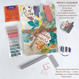 May include: A gift set for book lovers, featuring a floral-wrapped package tied with twine. Includes a new book, tea bag, highlighter, stickers, magnetic bookmark, and annotation tabs. A Yogi tea bag and reading-themed stickers are also included.