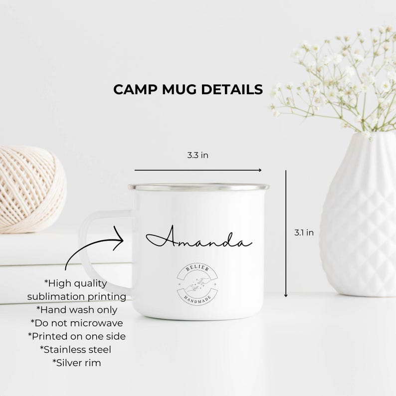 K&ouml;nnte beinhalten: Wei&szlig;e Emaille-Campingtasse mit silbernem Rand. Die Tasse ist 8,4 cm breit und 7,9 cm hoch. Sie tr&auml;gt einen schwarzen handschriftlichen Namen "Amanda" und ein schwarz-wei&szlig;es Logo mit der Aufschrift "Believer Handmade".