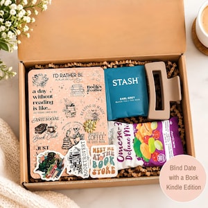 May include: A cardboard gift box filled with crinkle paper containing a notebook with book-themed stickers, a teal Stash Earl Grey tea bag, a matte beige hair claw clip, and a purple bag of Omega-3 Deluxe Mix nuts and dried fruit.