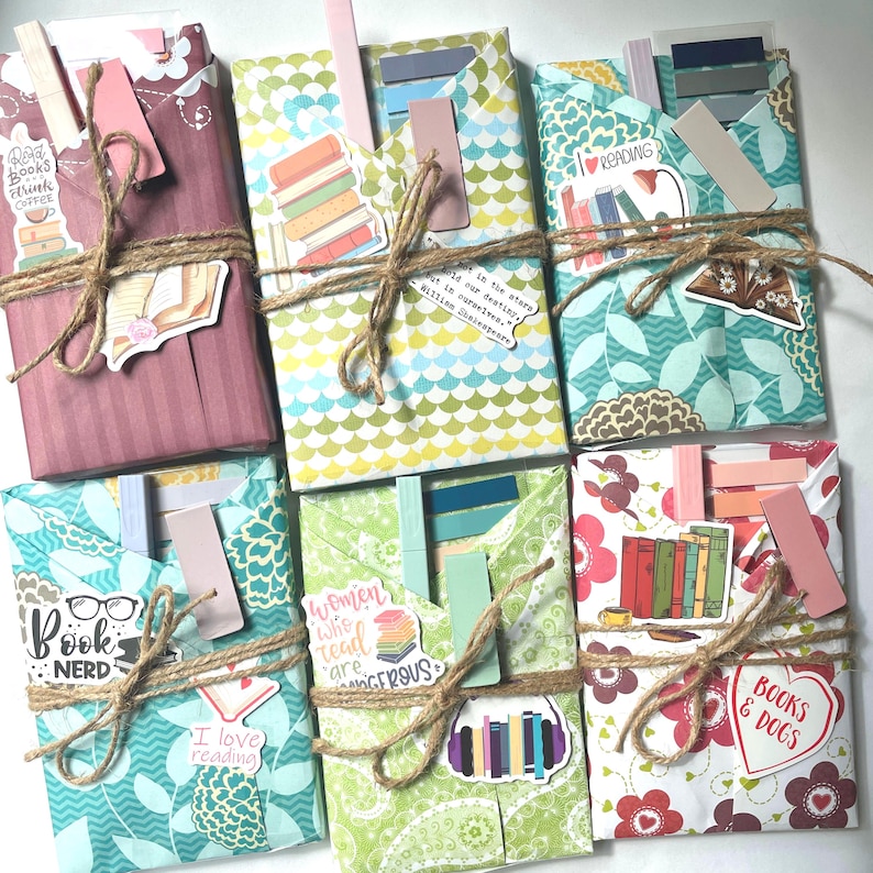 May include: An overhead shot of several wrapped books, each with a unique patterned paper cover. They are tied with twine and adorned with stickers and bookmarks. The stickers feature phrases like "Books & Dogs" and "Book Nerd."