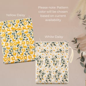 May include: Two floral patterned pouches are shown, one with yellow daisies and the other with white daisies. The text "Yellow Daisy" and "White Daisy" are above each pouch. The text "Please note: Pattern colour will be chosen based on current availability" is also present.