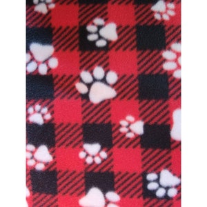 May include: Red and black plaid fabric with white paw prints. The fabric has a soft, fuzzy texture.