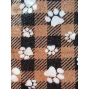 May include: Brown and black plaid fabric with a white paw print pattern.