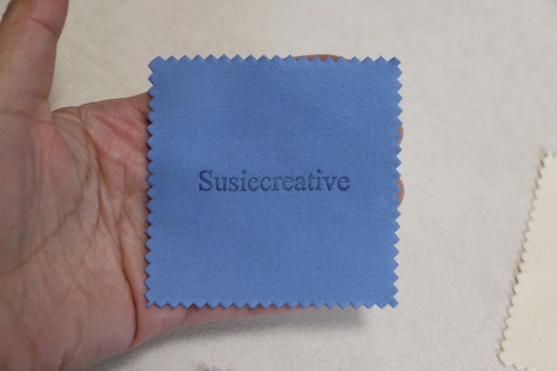 May include: A blue microfiber cleaning cloth with the text "SusieCreative" printed in white.