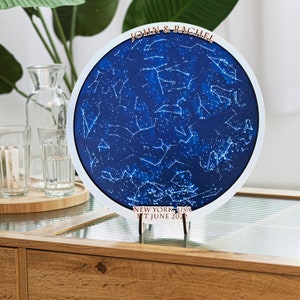 May include: A white circular wooden plaque with a blue star map, the text "JOHN & RACHEL", "NEW YORK, USA", and "17 JUNE 2021".