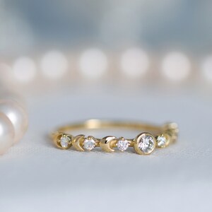 K&ouml;nnte beinhalten: Ein zarter Goldring mit einem Halbmond-Design und kleinen Diamanten. Der Ring hat einen gr&ouml;&szlig;eren runden Diamanten in der Mitte.