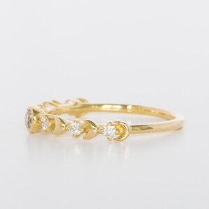 K&ouml;nnte beinhalten: Ein Goldring mit einem Halbmond-Design und kleinen Diamanten, die in die Band eingefasst sind.